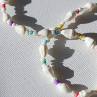 Close-up of a handmade shell bead necklace with colorful beads, reflecting a tropical beach-inspired aesthetic.